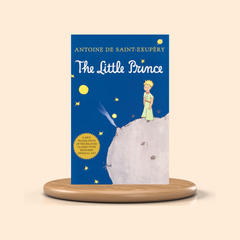 Book cover of 'The Little Prince' by Antoine de Saint-Exupéry on a wooden stand with a beige background